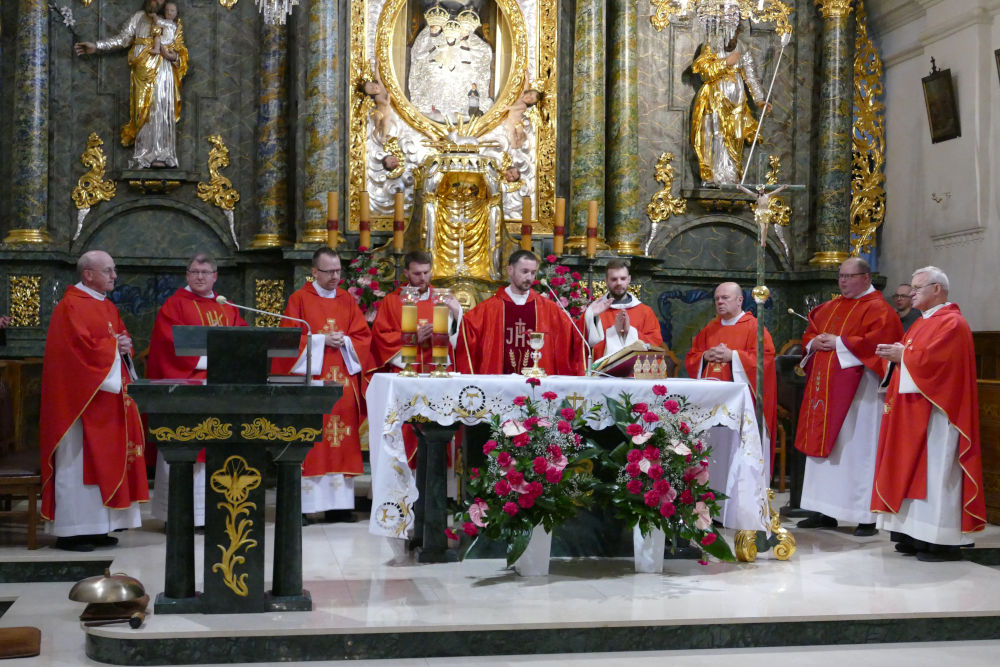 Kapłani w czerwonych ornatach sprawujący Eucharystię przy Ołtarzu