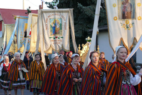 Kobiety oraz mczyni w strojach ludowych nioscy sztandary w Procesji Rezurekcyjnej.