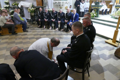 Kapłan myjący nogi ludziom siedziącym na krzesłach przed Ołtarzem