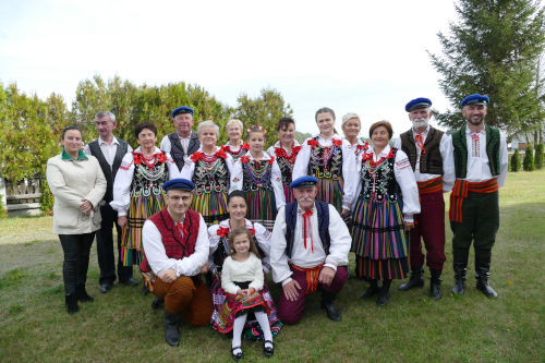 Ludzie w strojach ludowych stojcy na trawie.