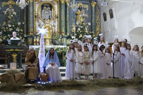 Dzieci przedstawiajce jaseka. Po lewo przy ambonie stoi lektor. Na rodku siedz dzieci przebrane za w. Jzefa i Maryj. Po prawo stoj dzieci przebrane za anioki.