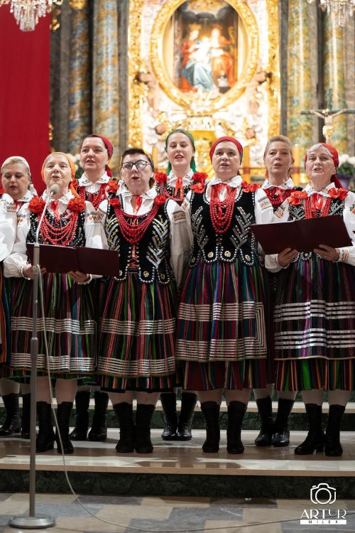 Dziewi piewajcych pa ubranych w stroje ludowe. Za nimi wida obraz w. Anny i jej Rodzicw oraz Tabernakulum.