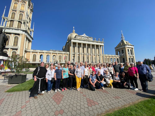 Grupa pielgrzymkowa stojąca na placu przed Sanktuarium Matki Bożej Licheńskiej