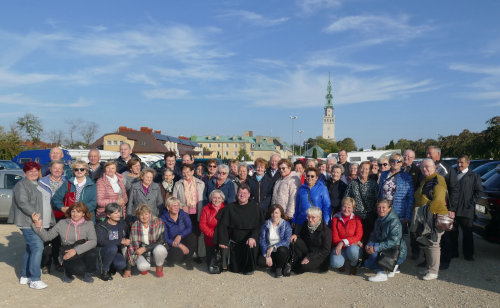 Zdjcie grupowe uczestnikw pielgrzymki. W tle wysoka wierza kocielna oraz budynki.