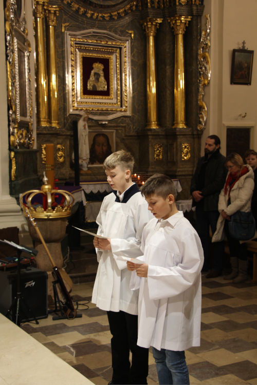 Dwch modych ministrantw w komach, czytajcych z kartek. Stoj przed Otarzem.